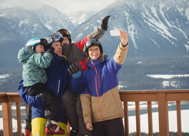happy family taking selfie on mobile phone during winter